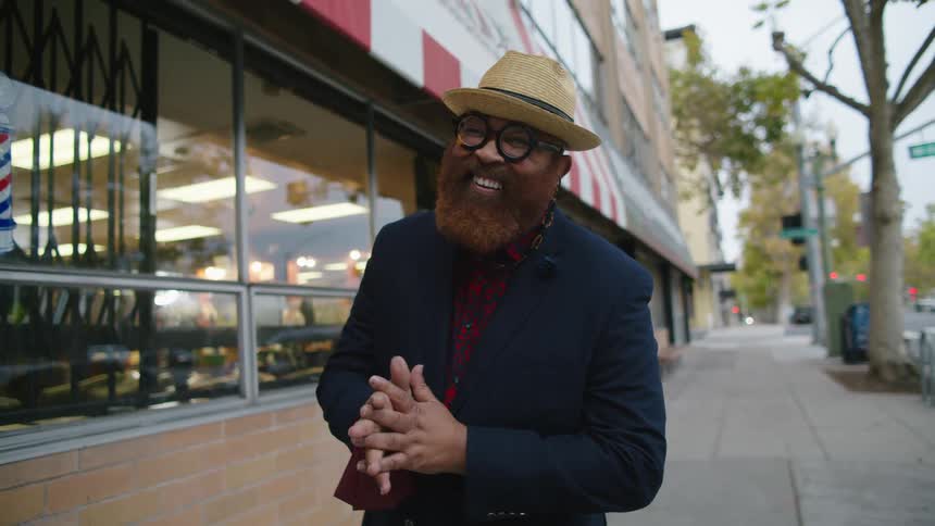 A man is smiling and standing outside of a building