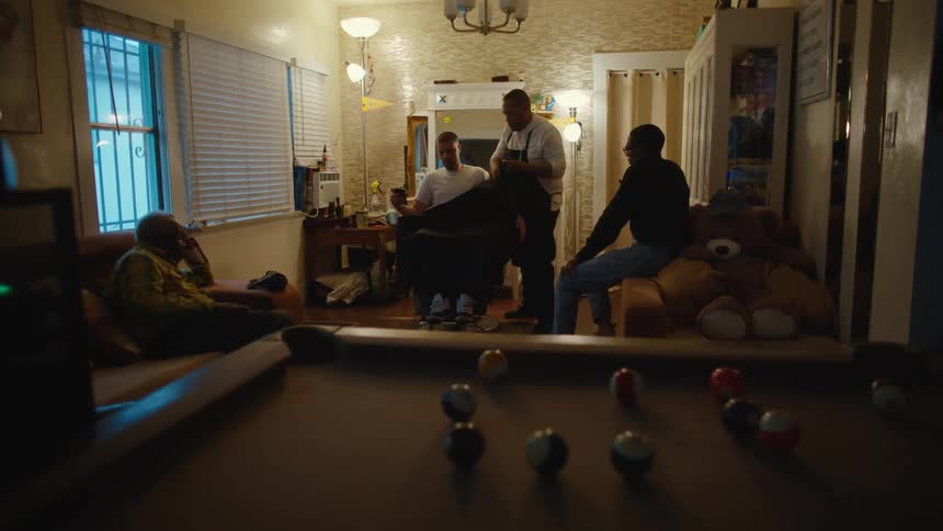 A group of people inside a house getting a hair cut