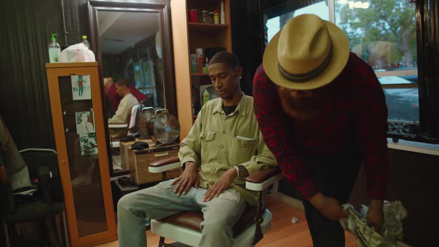 Barber removes the cape from a client sitting on a chair in the barber shop