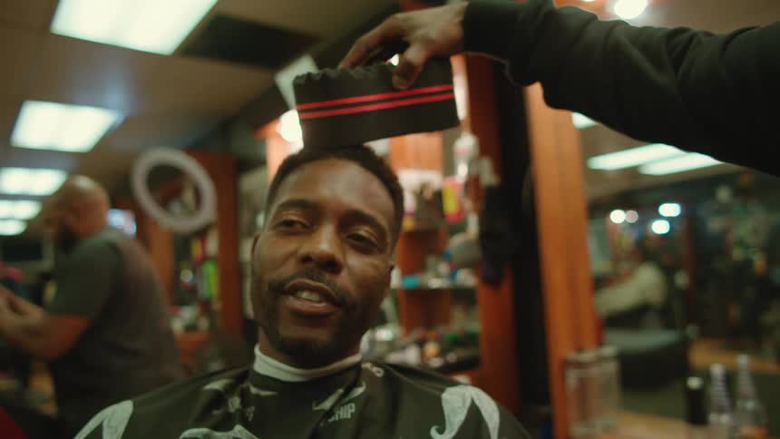 A man laughs as a barber rubs a sponge on his head