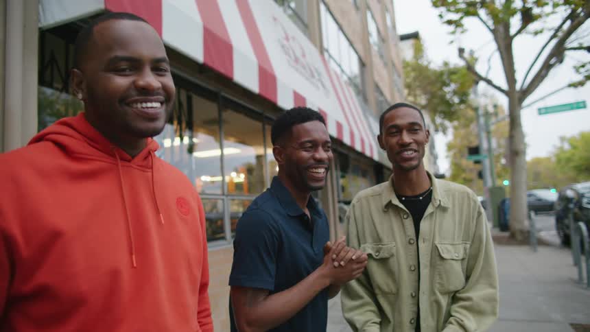 Three friends are talking outdoors next to a store