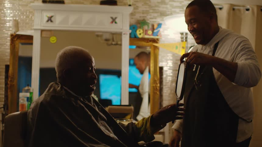 Barber hands mirror to client to allow them to see themselves