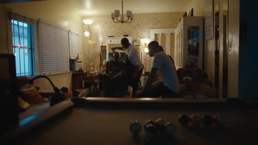 Barber shaving a clients head with an electric shaver on a home barber shop