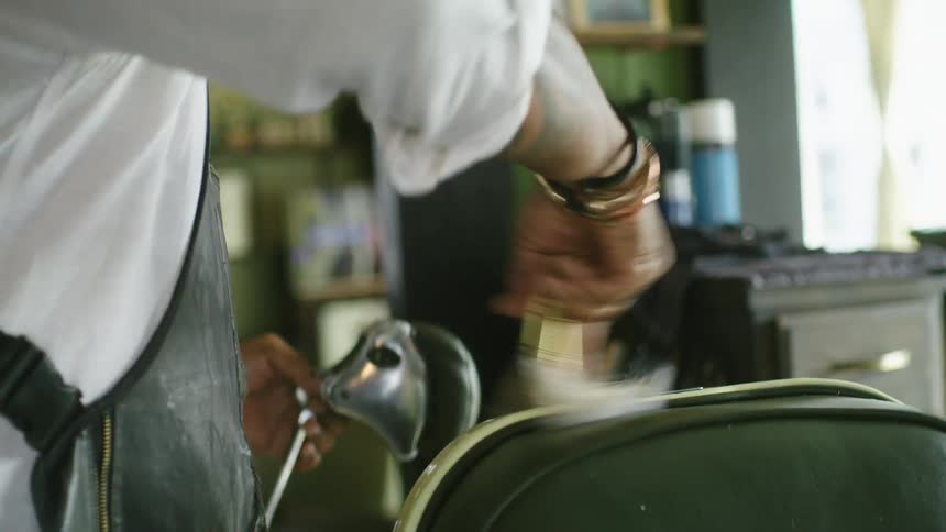 Barber wearing apron cleans hair from chair