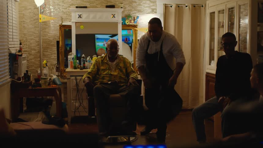A barber removes the apron from an elderly customer sitting in his barber chair