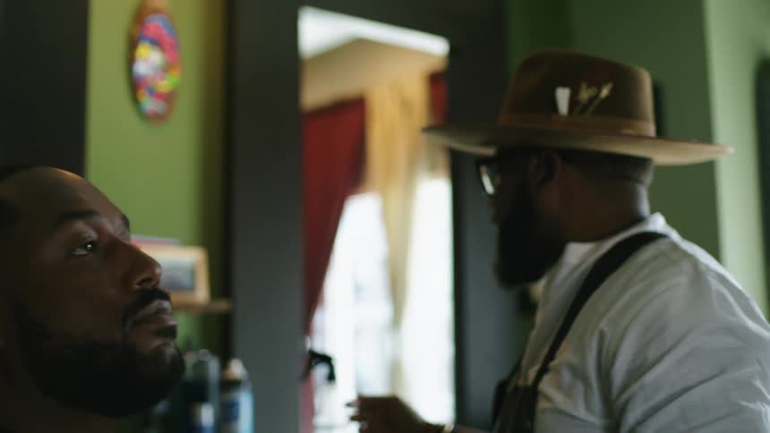 A barber putting beard oil on a persons face