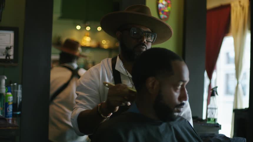 Barber brushes hair off client sitting in barber chair