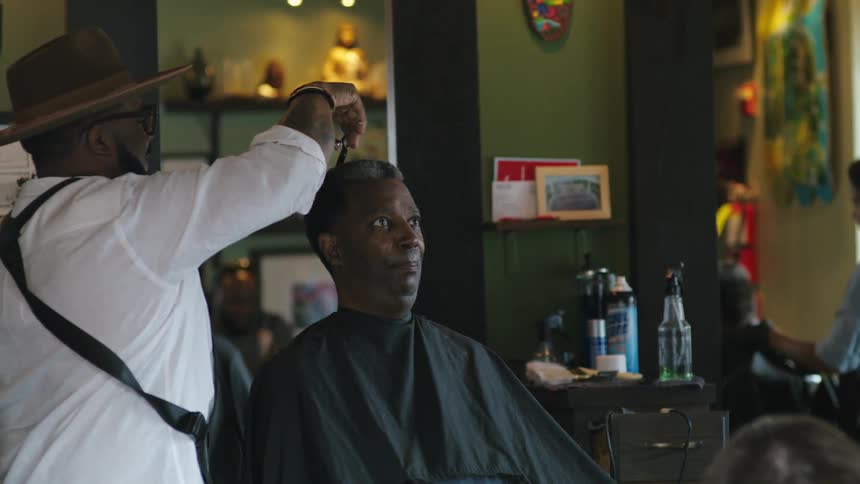 Two people cut customers hair in a salon