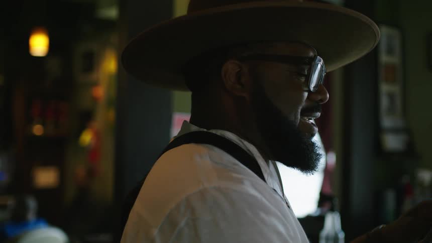 Barber with hat glasses beard white shirt and apron cuts mans hair in barber shop