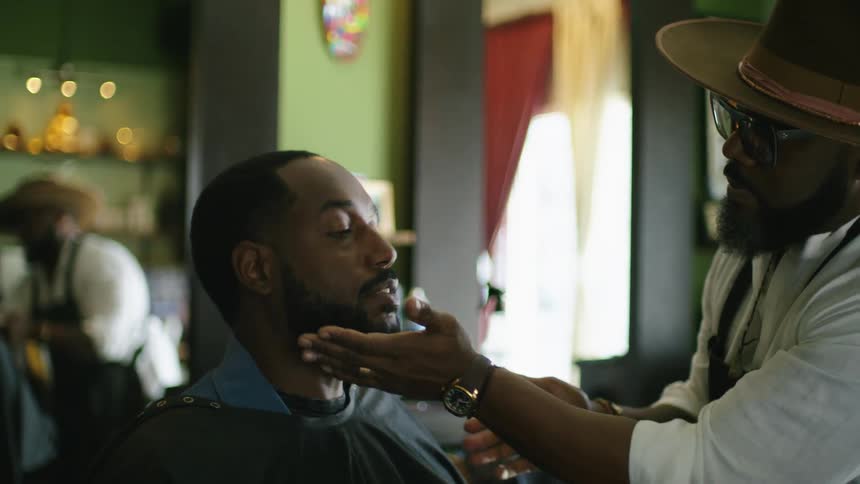Barber strokes customers beard as they talk