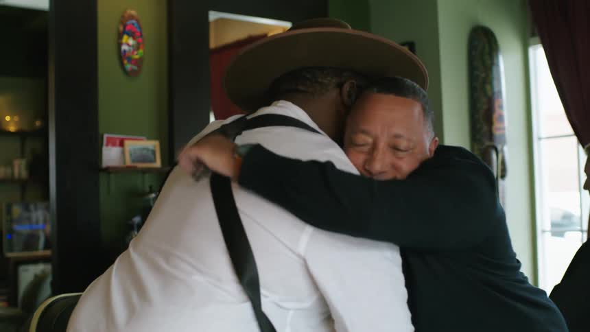 Client pays a barber for his services and hugs him as goodbye