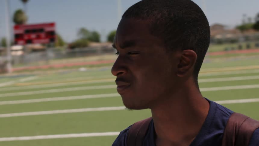 A young man looks around a football field
