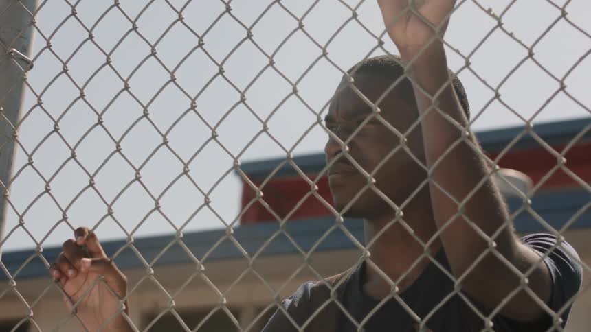 A man looks through a fence