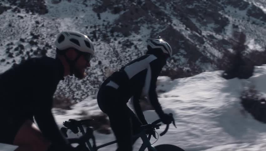 Two people are riding bikes outdoors in winter