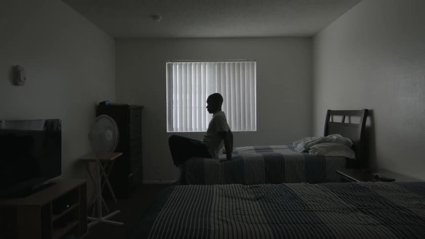 A bedroom has two beds with one person getting up from one