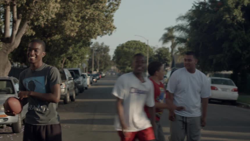 A group of kids play basketball in the street