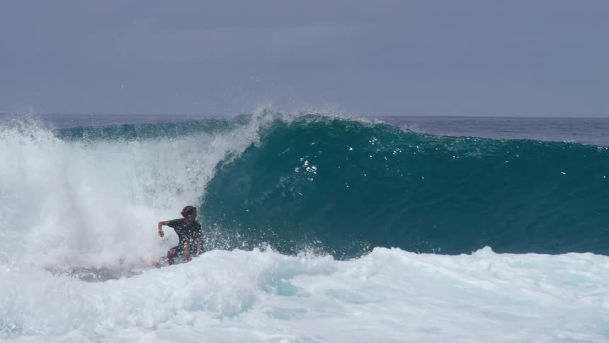 A male surfer riding an ocean wave on a sunny summer day