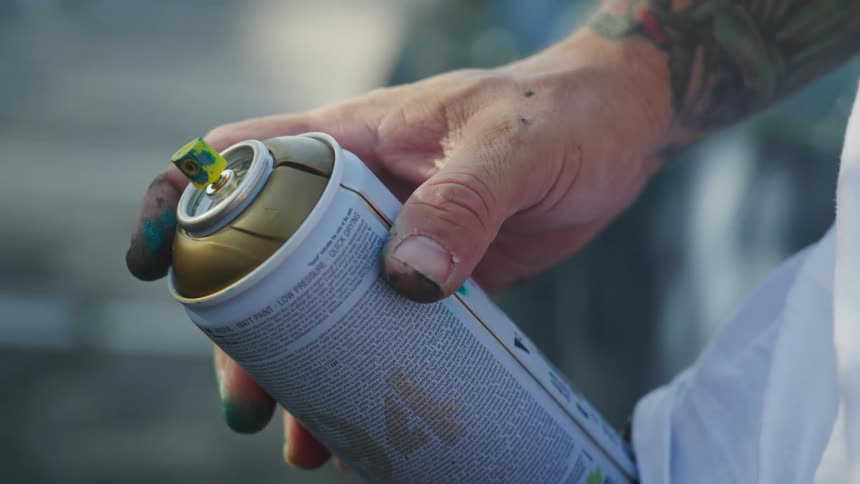 A man holds a can of spray paint