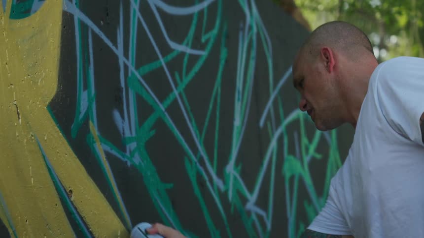 A man is spray painting a wall outdoors during spring