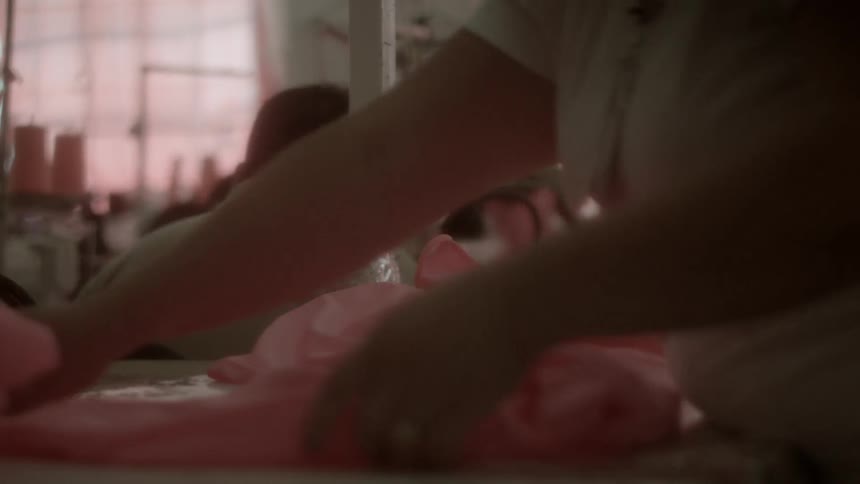 A person folds a pink piece of cloth
