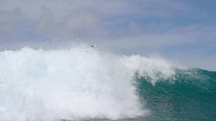 A boy is surfing on ocean water waves in spring