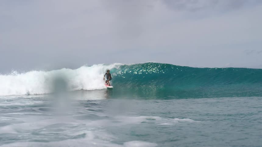 A man is surfing on ocean waves at midday