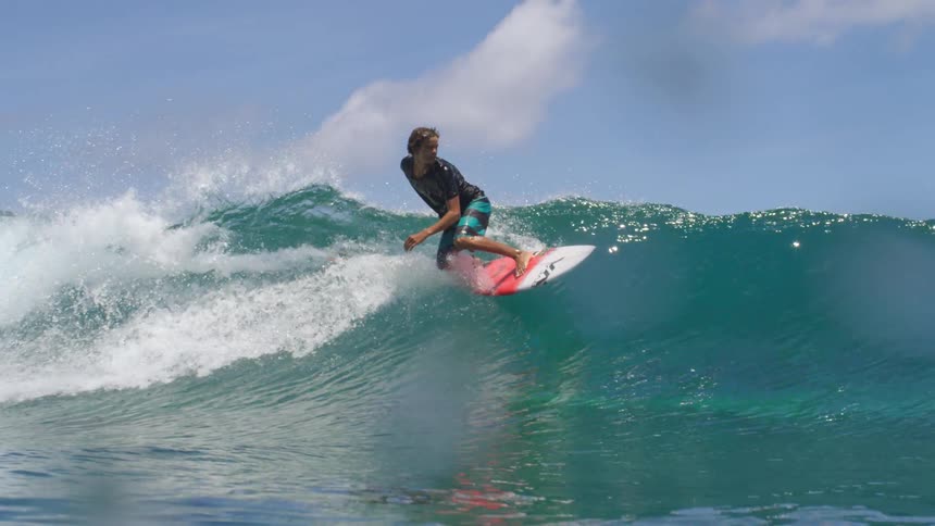 A male is surfing on ocean waves at midday