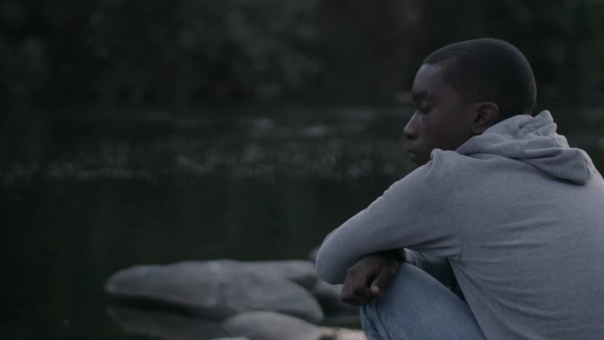 A man is crouched by the water