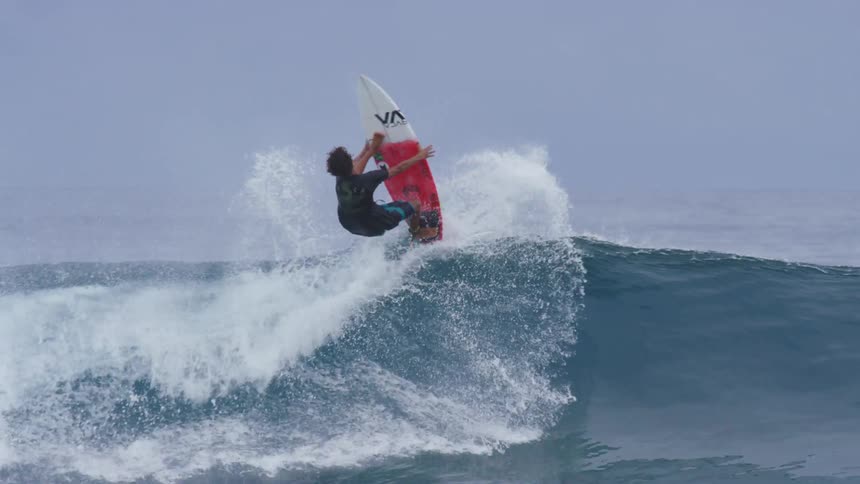 A man is surfing in ocean water during the daytime