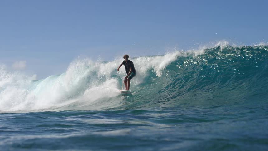 A man is surfing on ocean waves during the day