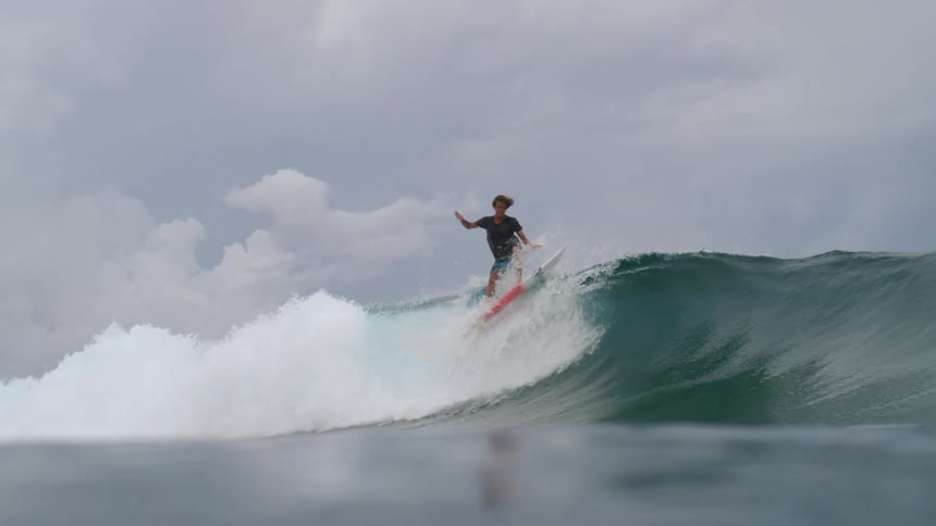 A male is surfing on ocean waves during midday