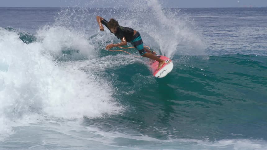 Teen surfer with black t shirt and shorts rides ocean wave