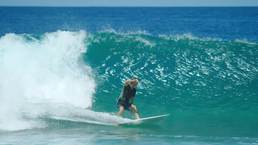Young man riding a wave in the ocean over a surfboard