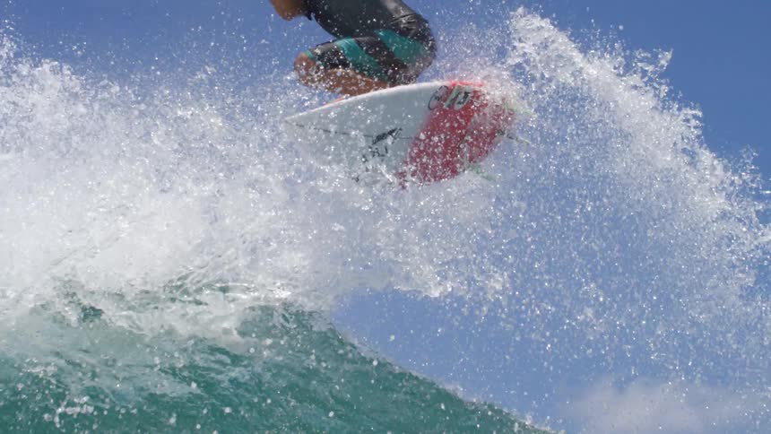 A surfer spins in the air after surfing up a wave on the ocean during the day