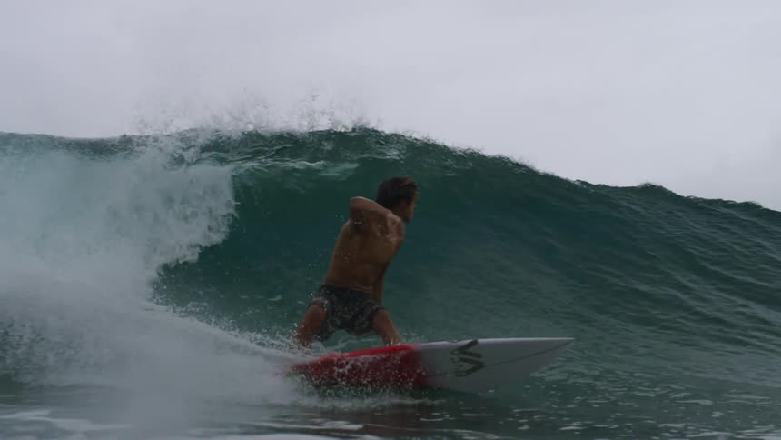 A teenage boy surfs a wave in the ocean and then flips over