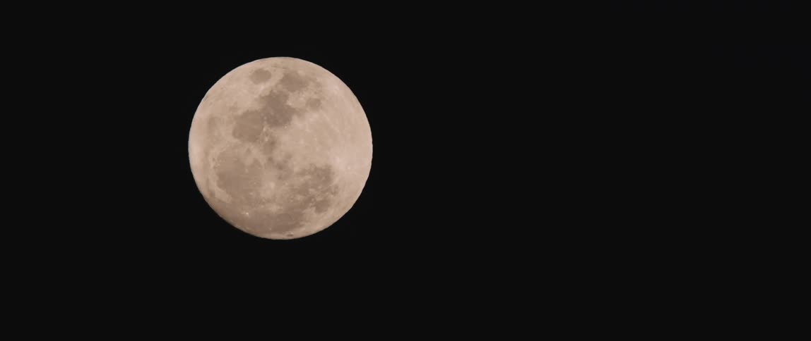 A full moon shines brightly in the dark night sky