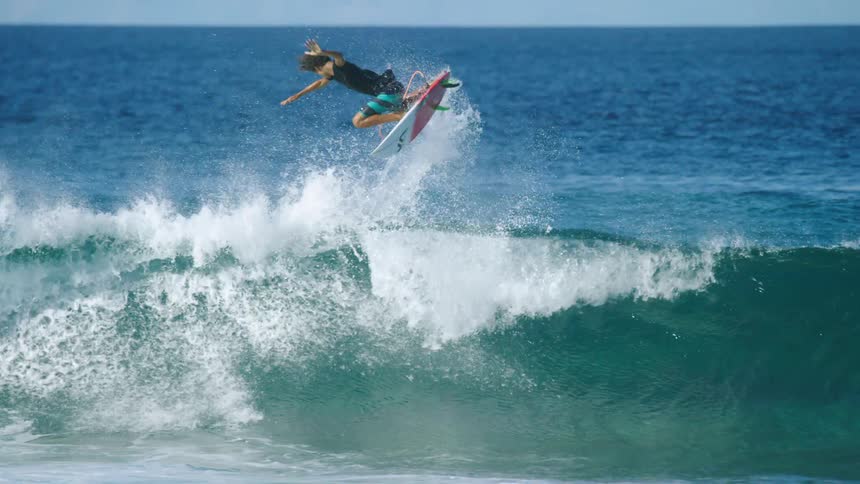 A boy is surfing on ocean waves at midday