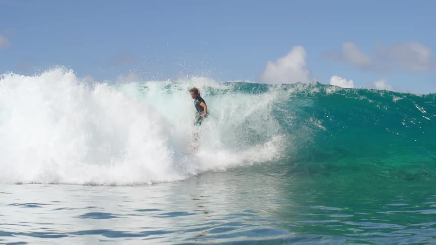 A teen is surfing on ocean waves at midday