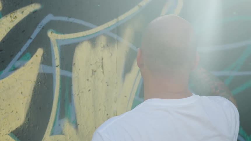 A man is painting an outdoors wall with spray paint