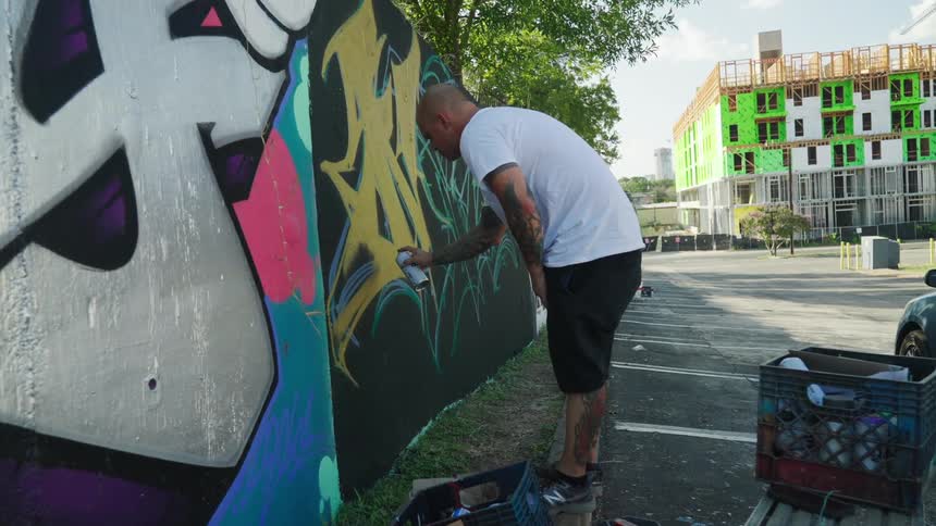 A man is spray painting a wall outdoors in spring