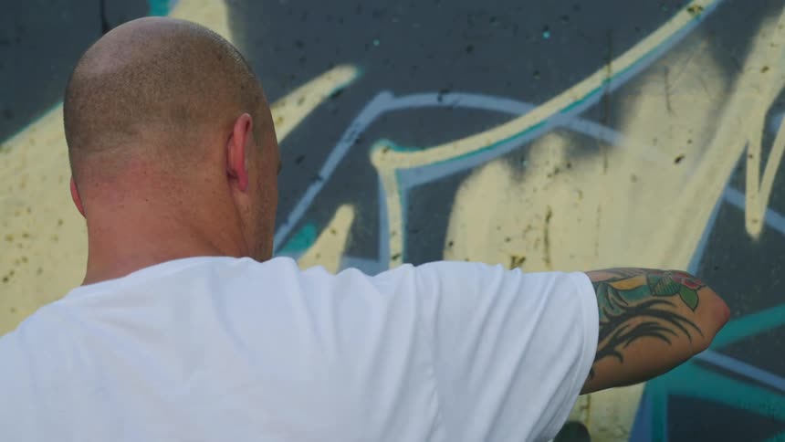 A man is spray painting a wall outdoors in spring