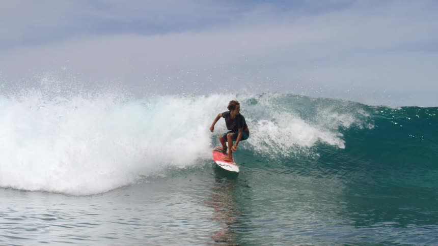 A male surfer riding an ocean wave on a sunny summer day