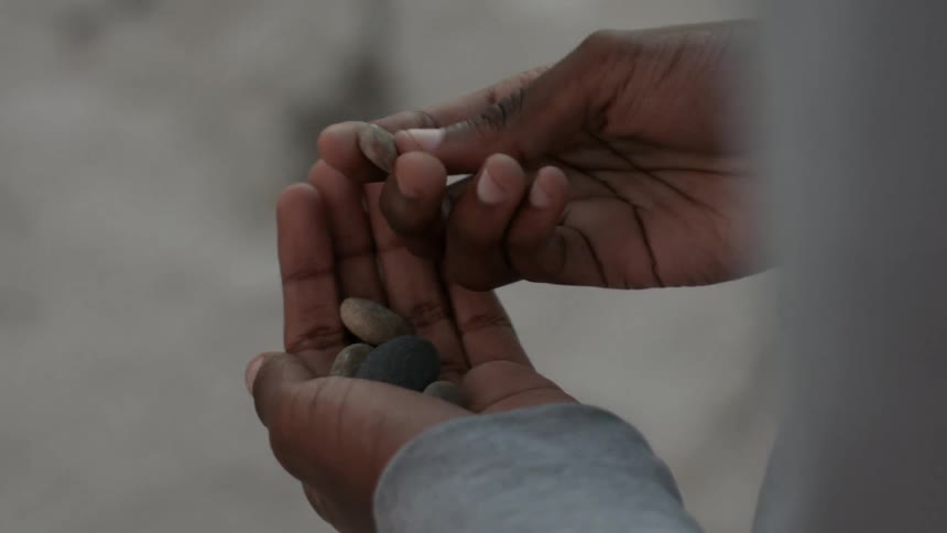 Two hands hold and rub pebbles