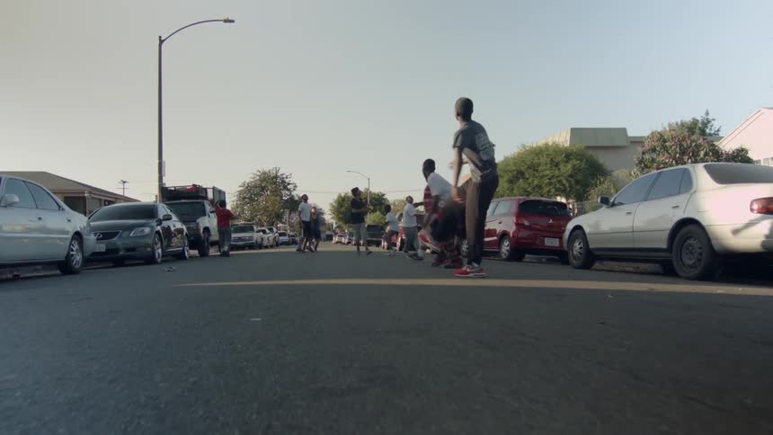 A group of young boys playing football in the middle of a street