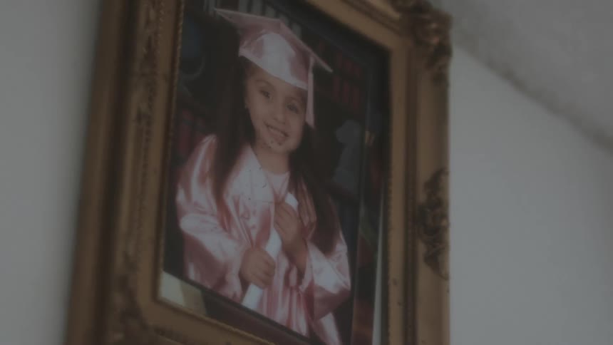 A portrait of a girl in a cap and gown hangs on the wall
