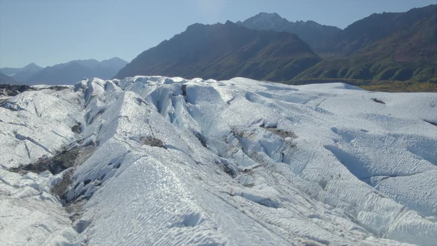 Aerial view of glacier with distant high mountains