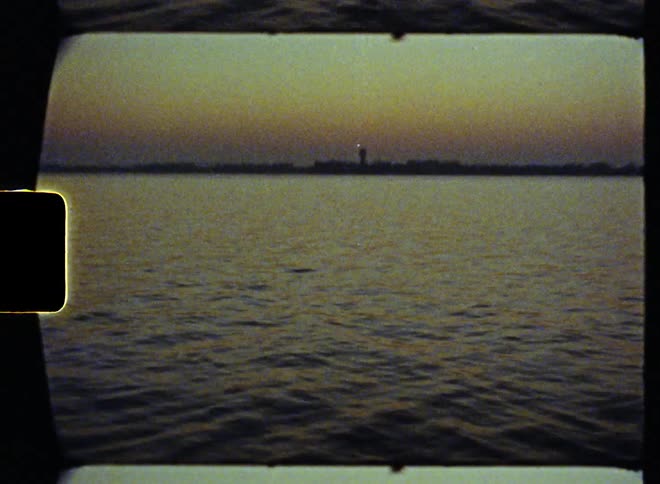 City skyline across the rippling water is silhouetted against the red sky on the horizon
