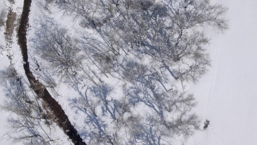 An aerial view of an icy river flowing through a snowy landscape in winter