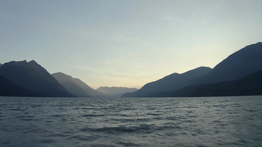 View of lake with mountains silhouetted against the sky at dusk