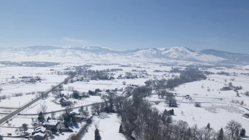 Aerial view of snowy countryside with distant mountains and clear sky